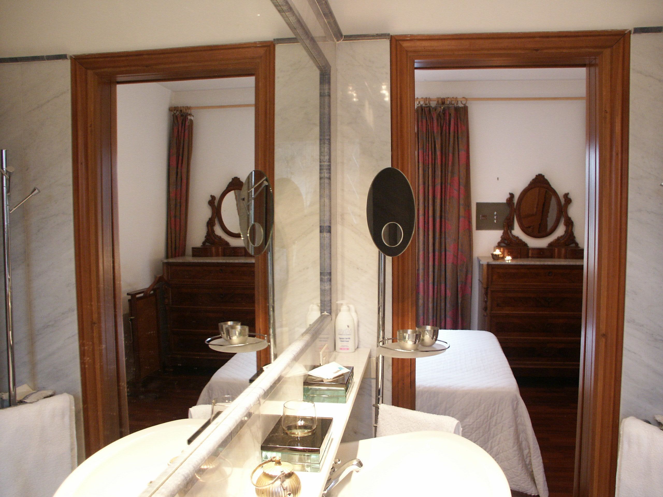 A bathroom with a large mirror, a vanity with a sink, and a towel rack.