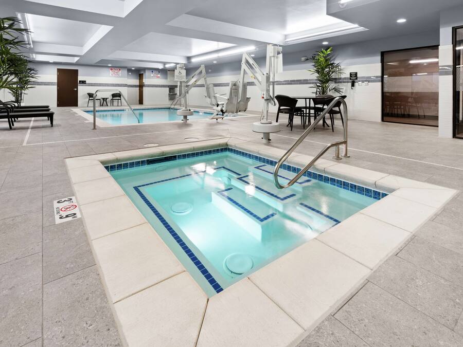 An indoor swimming pool with clear water, surrounded by lounge chairs and a seating area.
