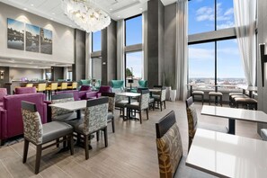 A modern hotel lobby with a large seating area, a reception desk, and large windows offering a city view. - Hampton Inn & Suites Spokane Downtown-South (Spokane)