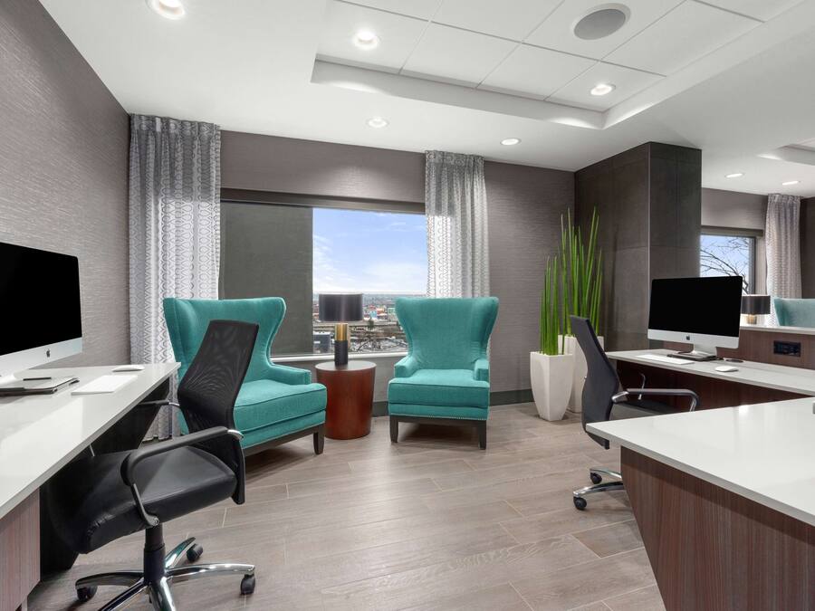 Een moderne kantoorruimte met teal stoelen, een wit bureau en een groot raam met uitzicht.