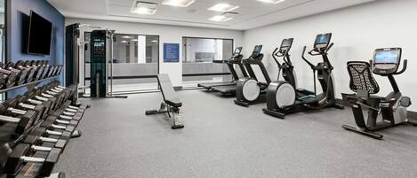 A gym with treadmills, elliptical machines, and dumbbells.