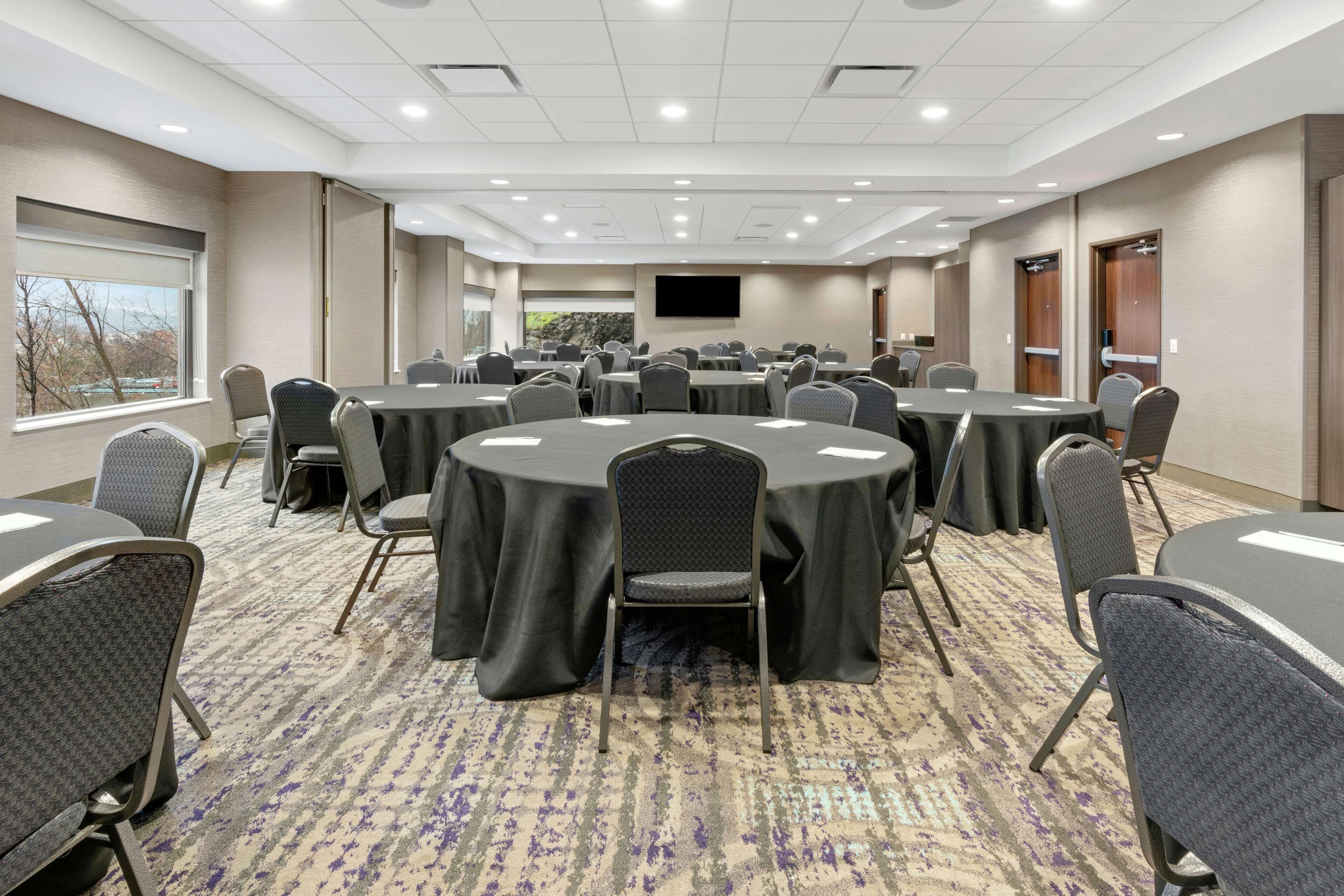 A conference room with round tables, chairs, and a large screen.