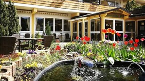 A hotel with a garden patio, outdoor seating, and a water feature. - Ferienhotel Schwarzwälder Hof (Feldberg)