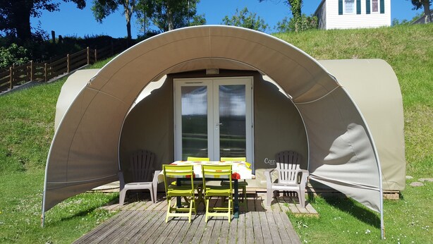 A covered outdoor seating area with a table and chairs, a door, and a small window. - Camping Le Mont Joli Bois (Criel-sur-Mer)