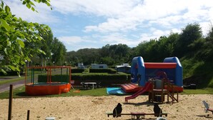 A playground with a trampoline, slides, and a sandpit. - Camping Le Mont Joli Bois (Criel-sur-Mer)