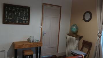 Une pièce comprenant une table en bois, une chaise, un radiateur, une porte et un globe terrestre posé sur un socle.