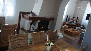 Una sala de estar con chimenea, muebles de mimbre, un televisor y un sofá.