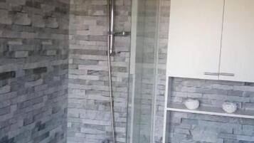 A bathroom with a stone wall, a bathtub, a shower, and a toilet.