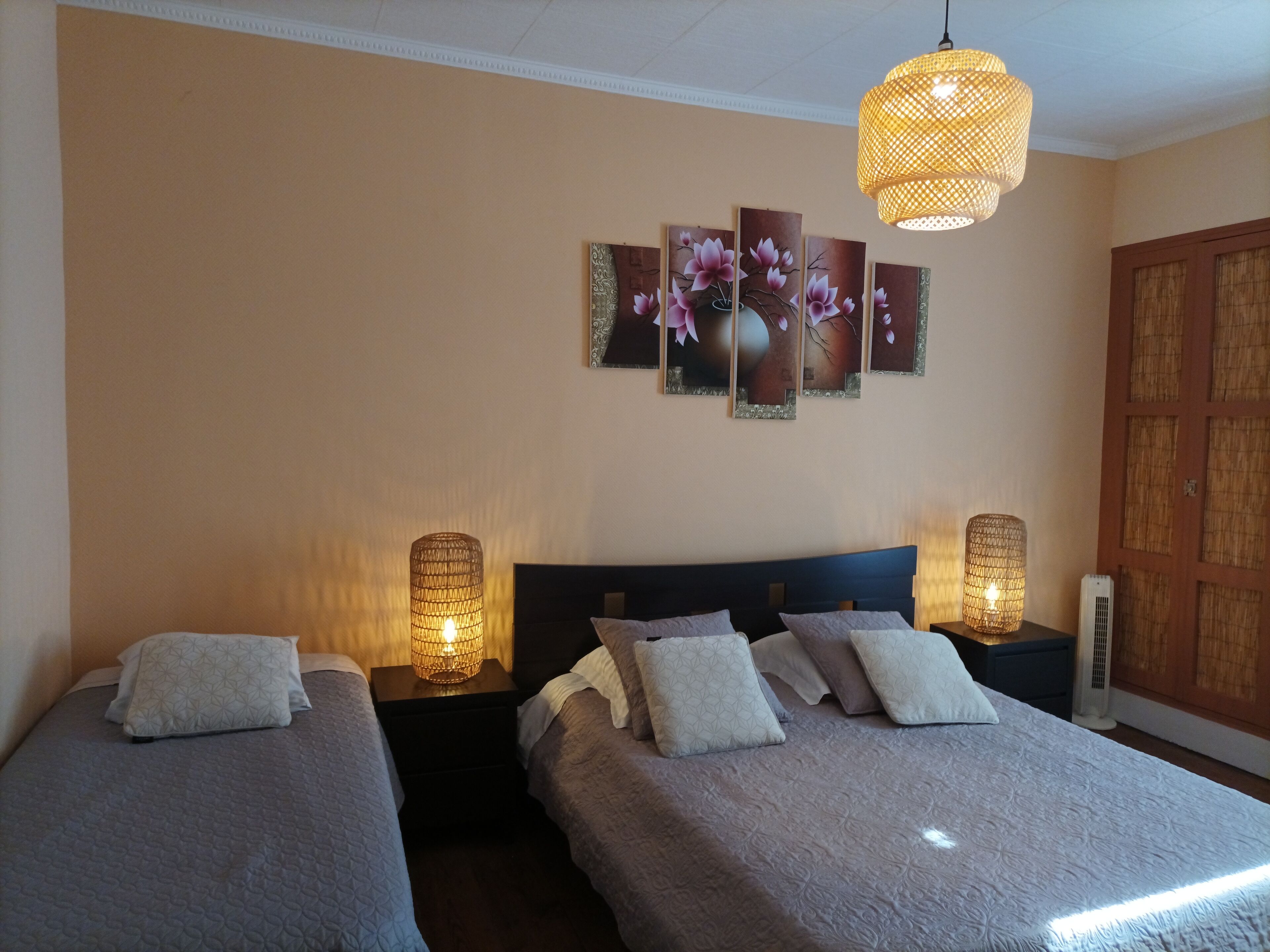 Ein Hotelzimmer mit zwei Betten, einem großen Blumenbild an der Wand und einer Pendelleuchte.