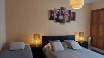 Ein Hotelzimmer mit zwei Betten, einem großen Blumenbild an der Wand und einer Pendelleuchte.