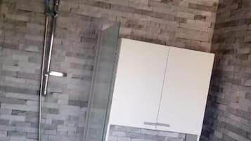 A bathroom with a shower, toilet, and a cabinet.