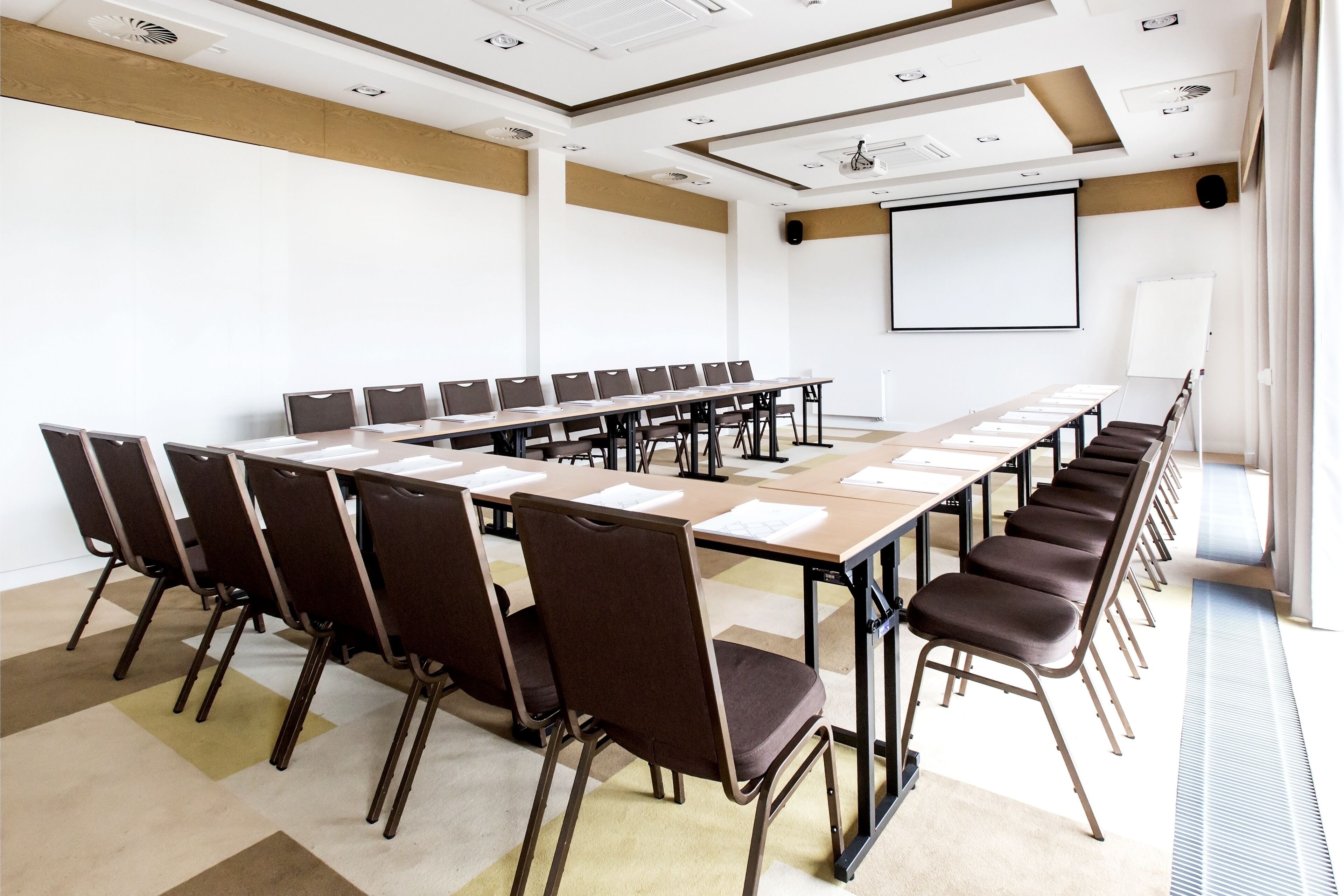 A conference room with a long table, chairs, a projector screen, and a whiteboard.