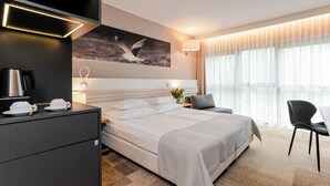 A modern hotel room with a large bed, bedside tables, a desk, and a view of the outdoors. - Hotel Platan (Gdansk)