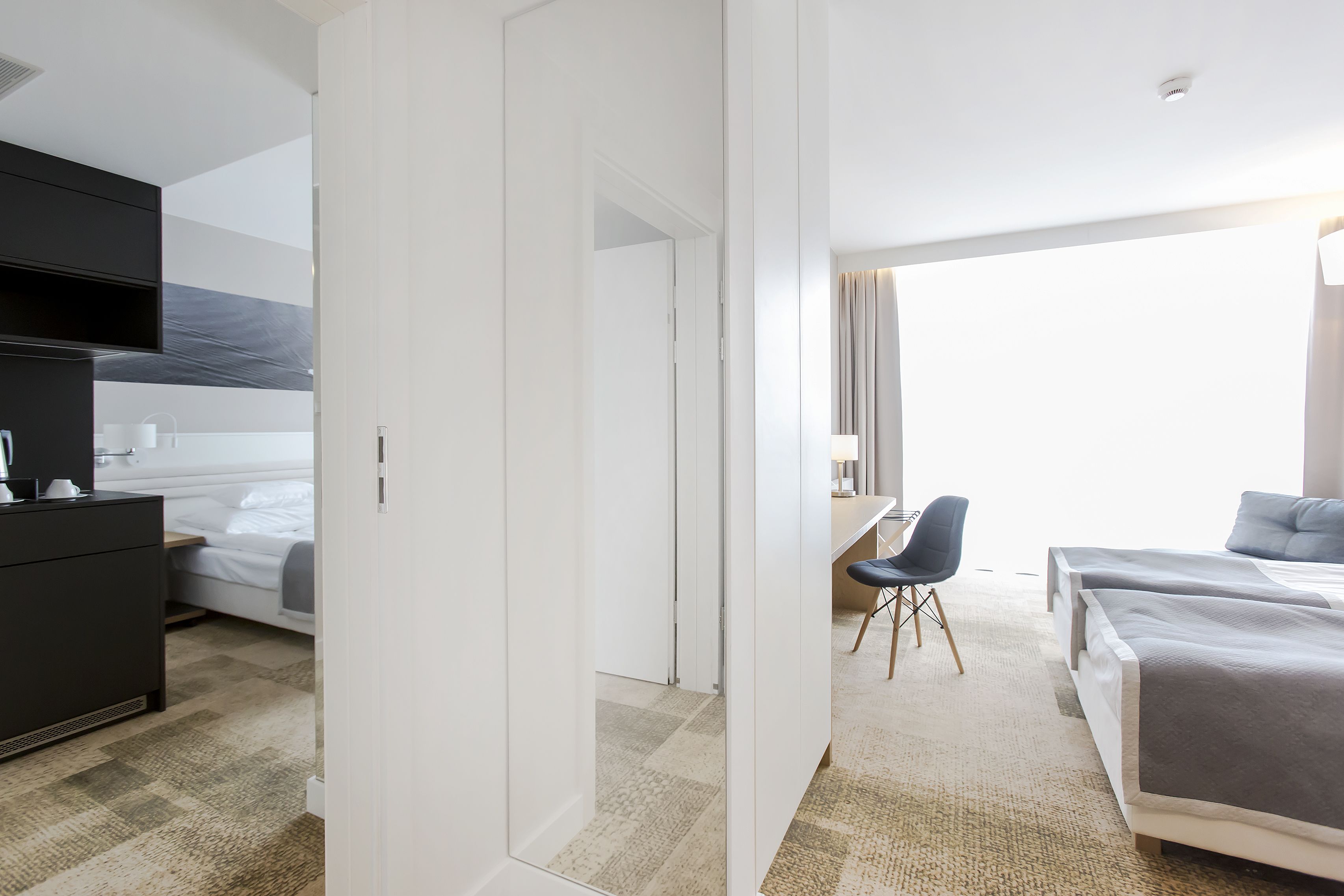 Et hotelværelse med seng, skrivebord, stol og garderobeskab.