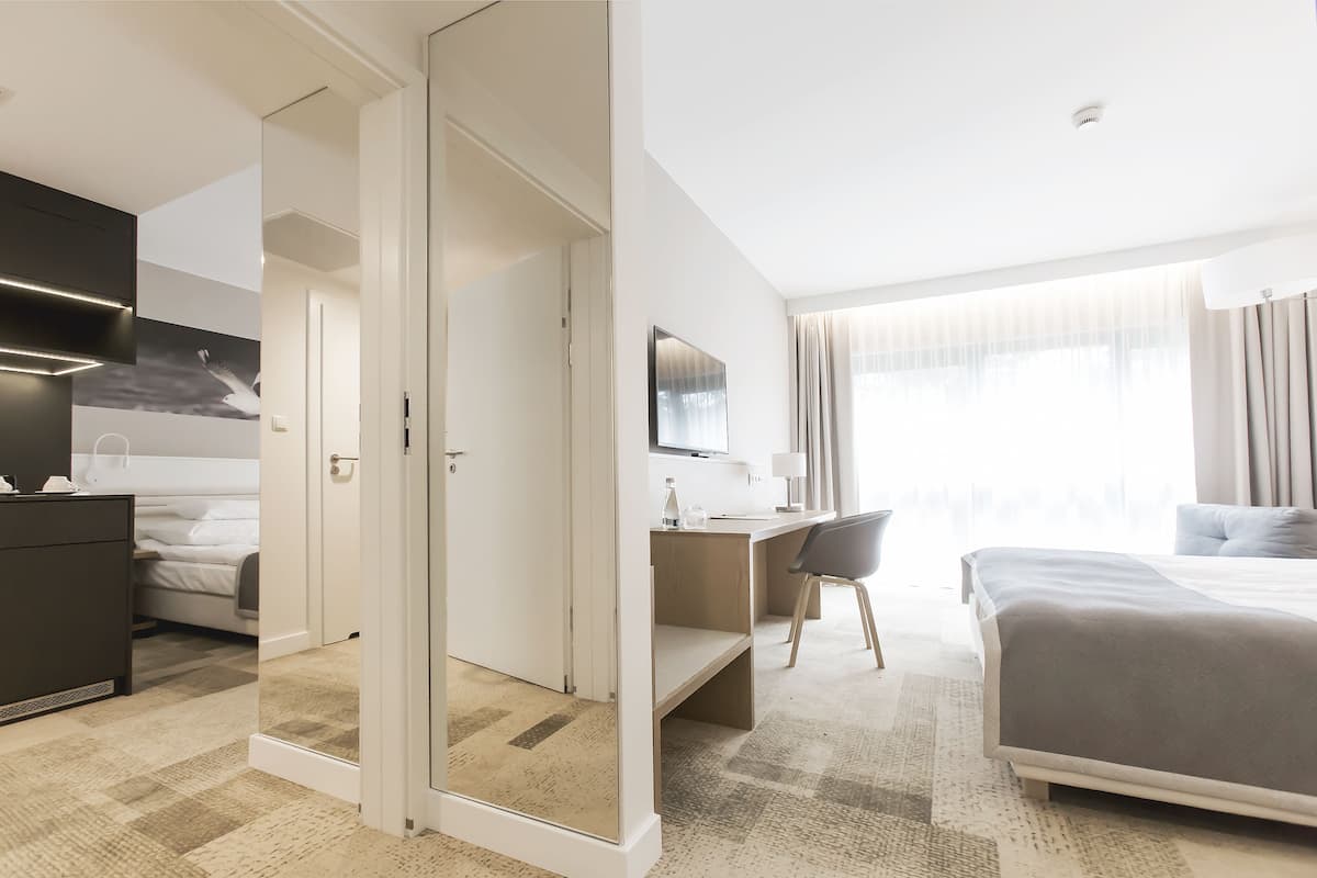 A hotel room with a bed, desk, and a wardrobe.