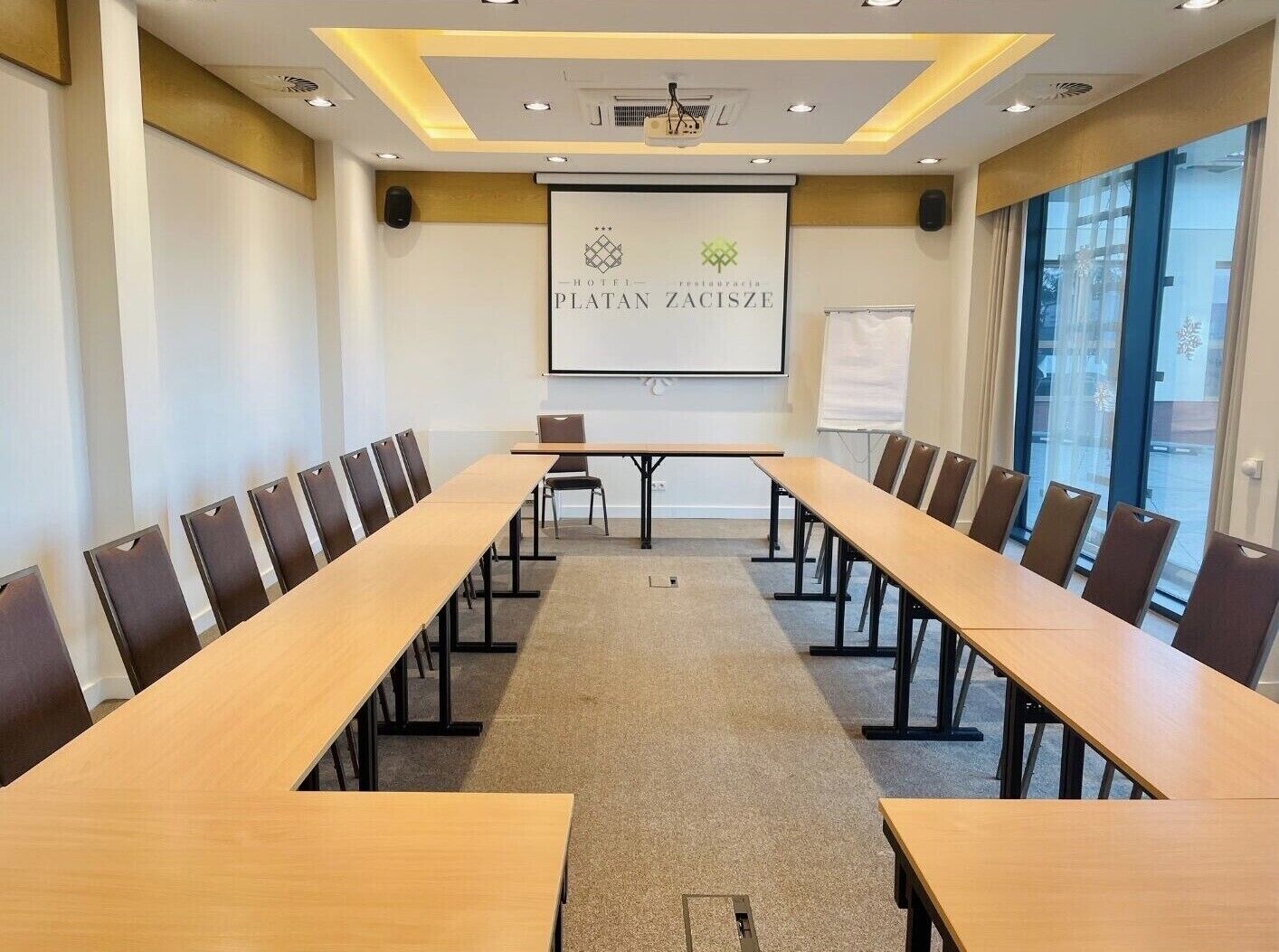 Ett konferensrum med ett långt bord och stolar, en projektorduk och en whiteboard.