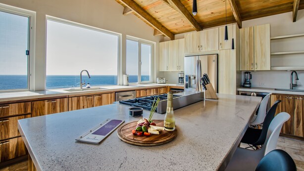 Una cocina moderna con armarios de madera, una isla grande y vistas al océano.