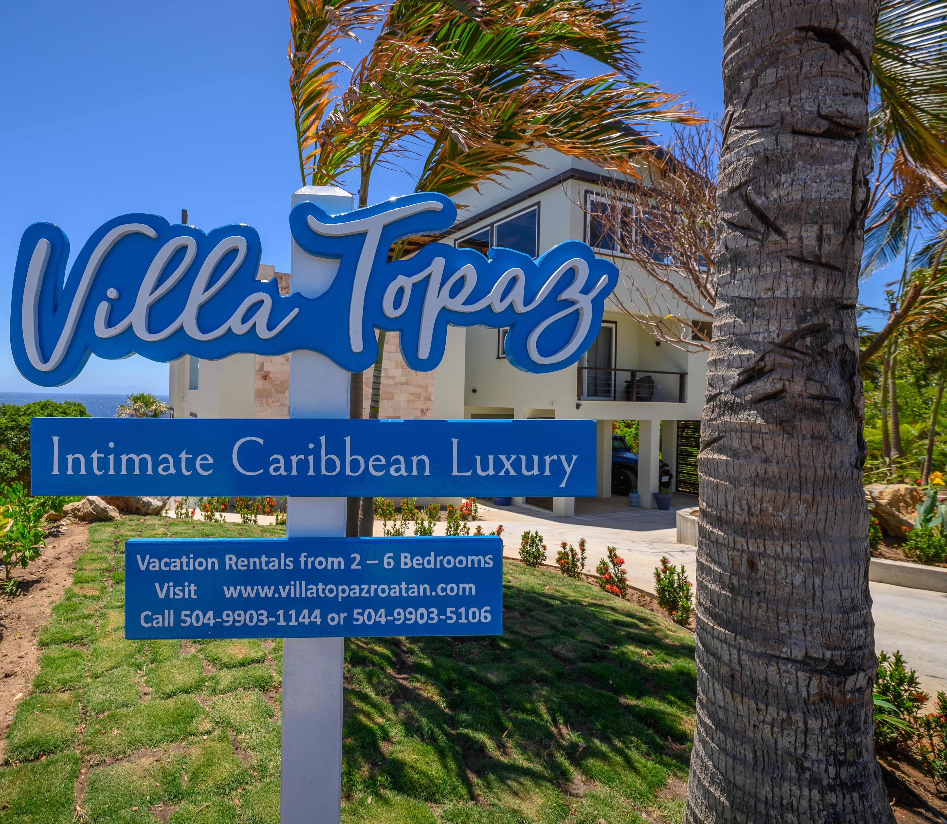Une enseigne pour Villa Topaz, une luxueuse villa de vacances dans les Caraïbes, offrant de 2 à 6 chambres, avec les coordonnées et l’adresse du site web.