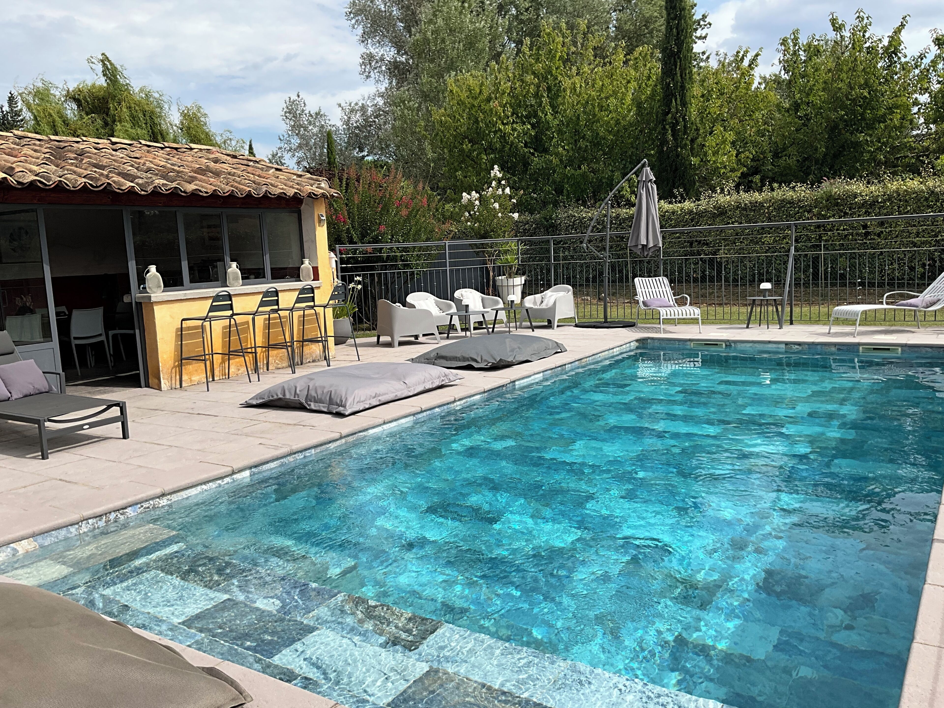 A swimming pool with lounge chairs and a bar area.