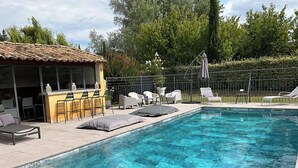 Piscina com espreguiçadeiras e área de bar.