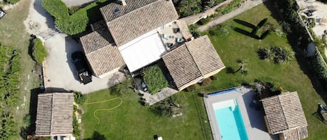 An aerial view of a residential area with multiple houses, a swimming pool, and a parking area.