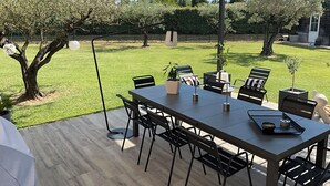 Um pátio externo com mesa de jantar, cadeiras e plantas em vasos.