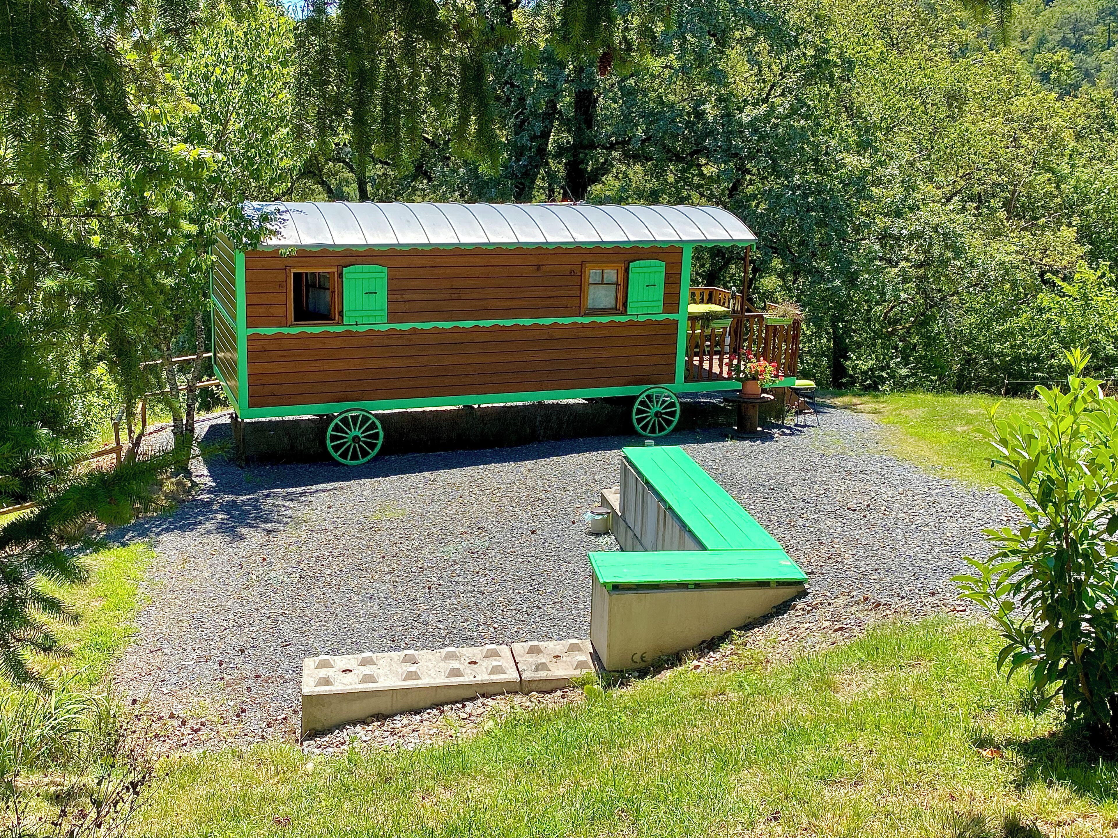 Uma casa de madeira com detalhes verdes, um alpendre e um caminho de acesso de cascalho.