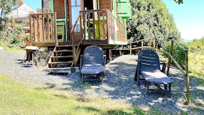 A wooden cabin with a balcony, two lounge chairs, and a gravel ground. - A wooden caravan at Domaine de la Morétie (CUBLAC)