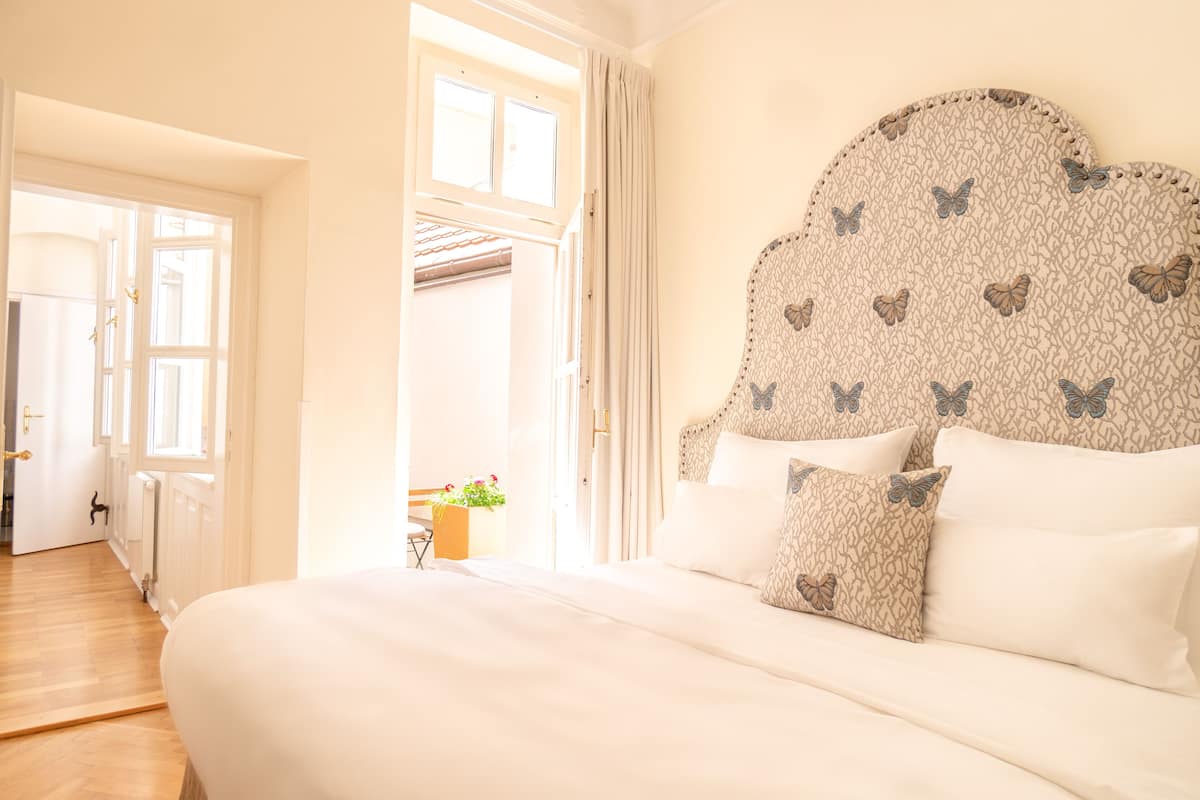 Un dormitorio con una cama grande, un cabecero con motivos de mariposas y vistas a un balcón con barandilla.