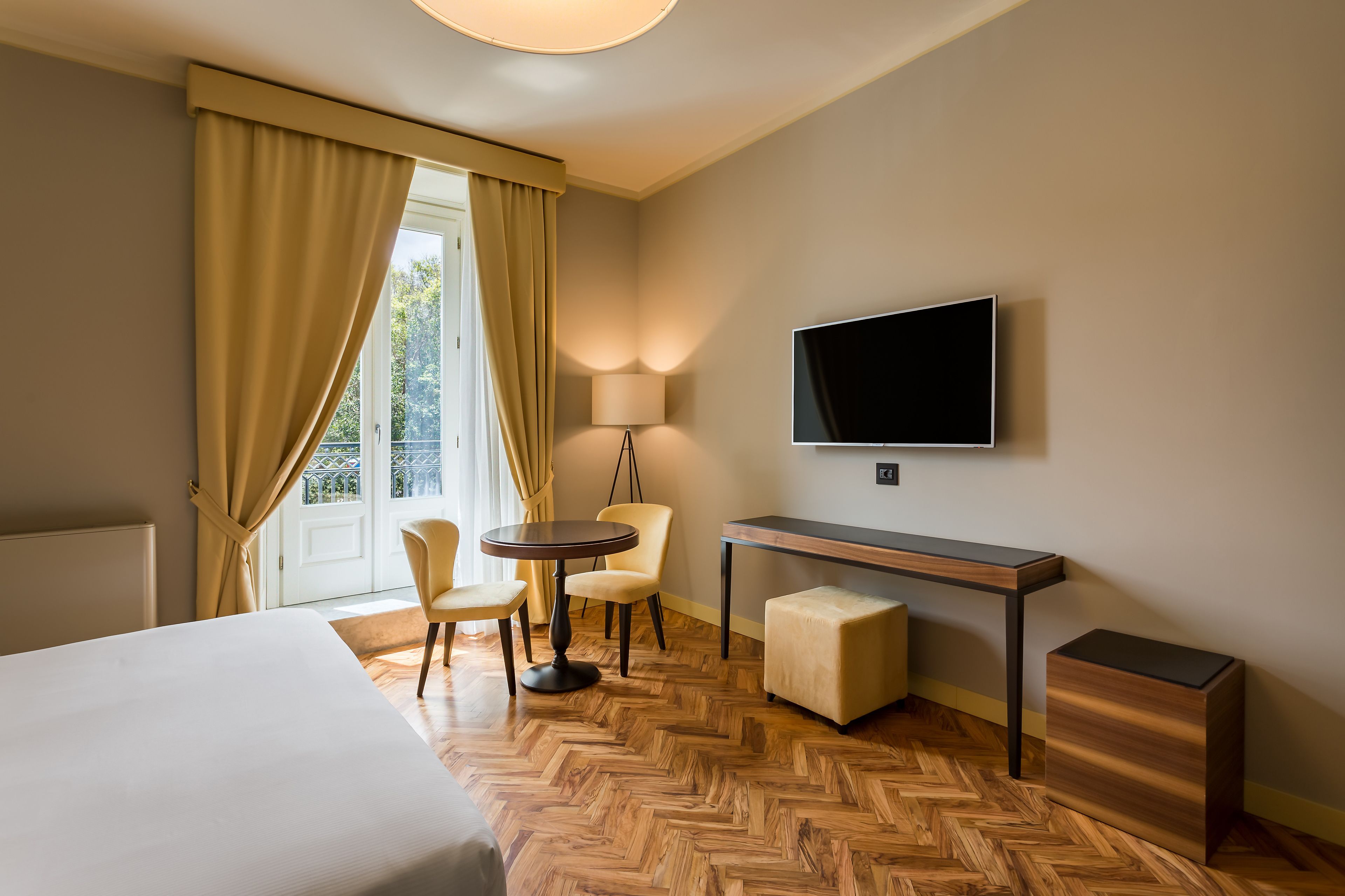 A hotel room with a bed, a desk, a TV, and a seating area with chairs.