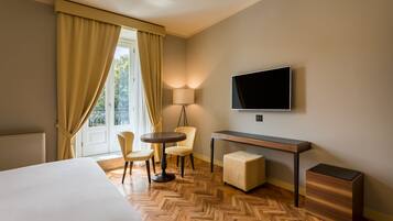 A hotel room with a bed, a desk, a TV, and a seating area with chairs.
