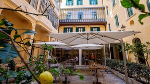 A courtyard with outdoor seating, a restaurant, and a building with balconies. - Room of Andrea (Trapani)
