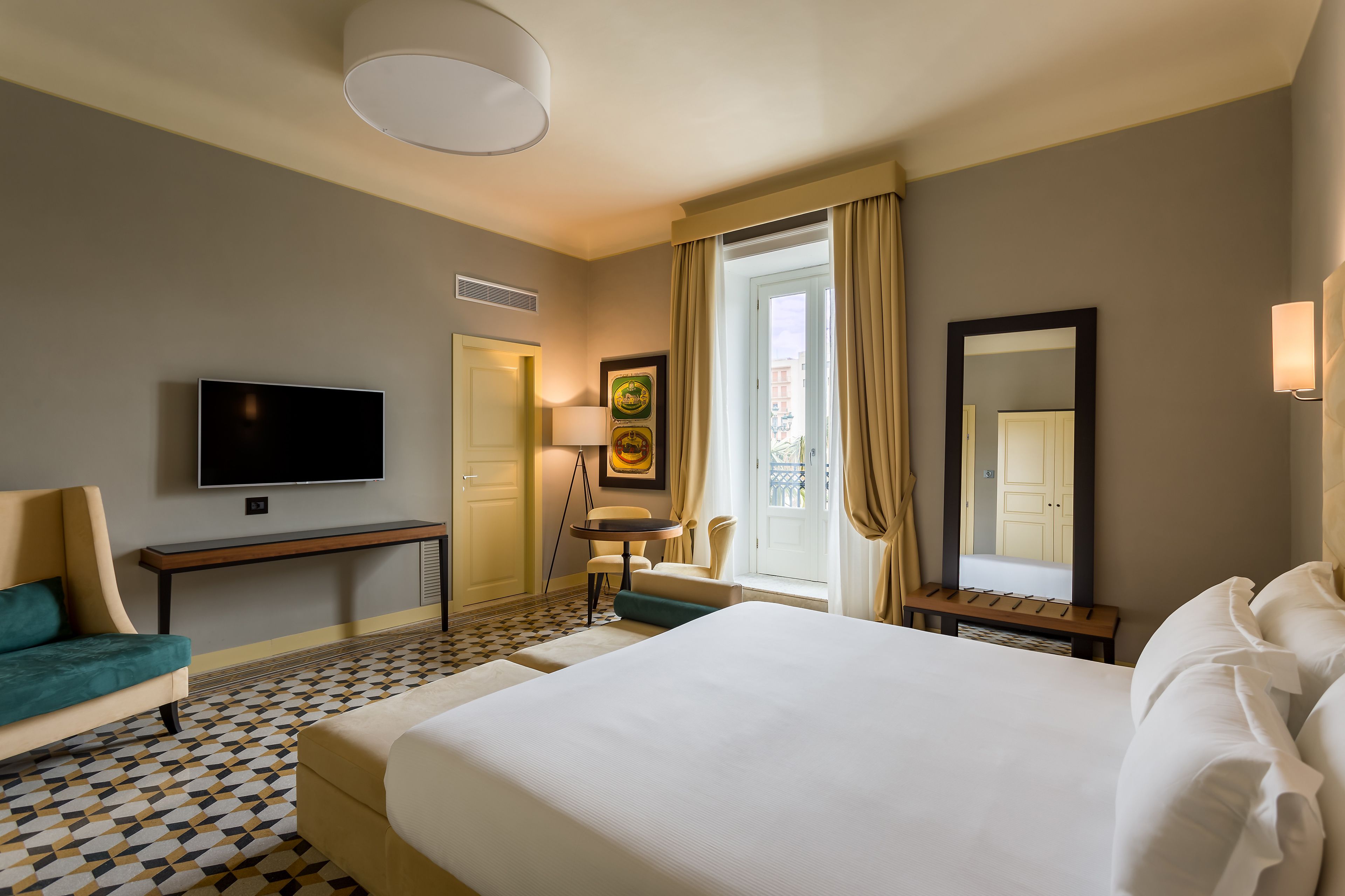 A hotel room with a large bed, a TV, a desk, and a chair.
