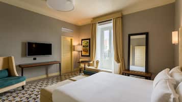 A hotel room with a large bed, a TV, a desk, and a chair.