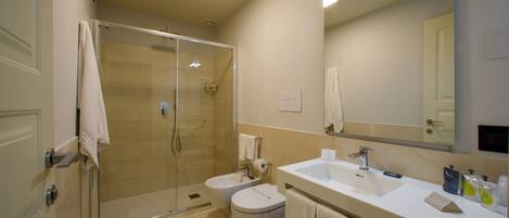 A modern bathroom with a glass-enclosed shower, two sinks, a toilet, and a large mirror.