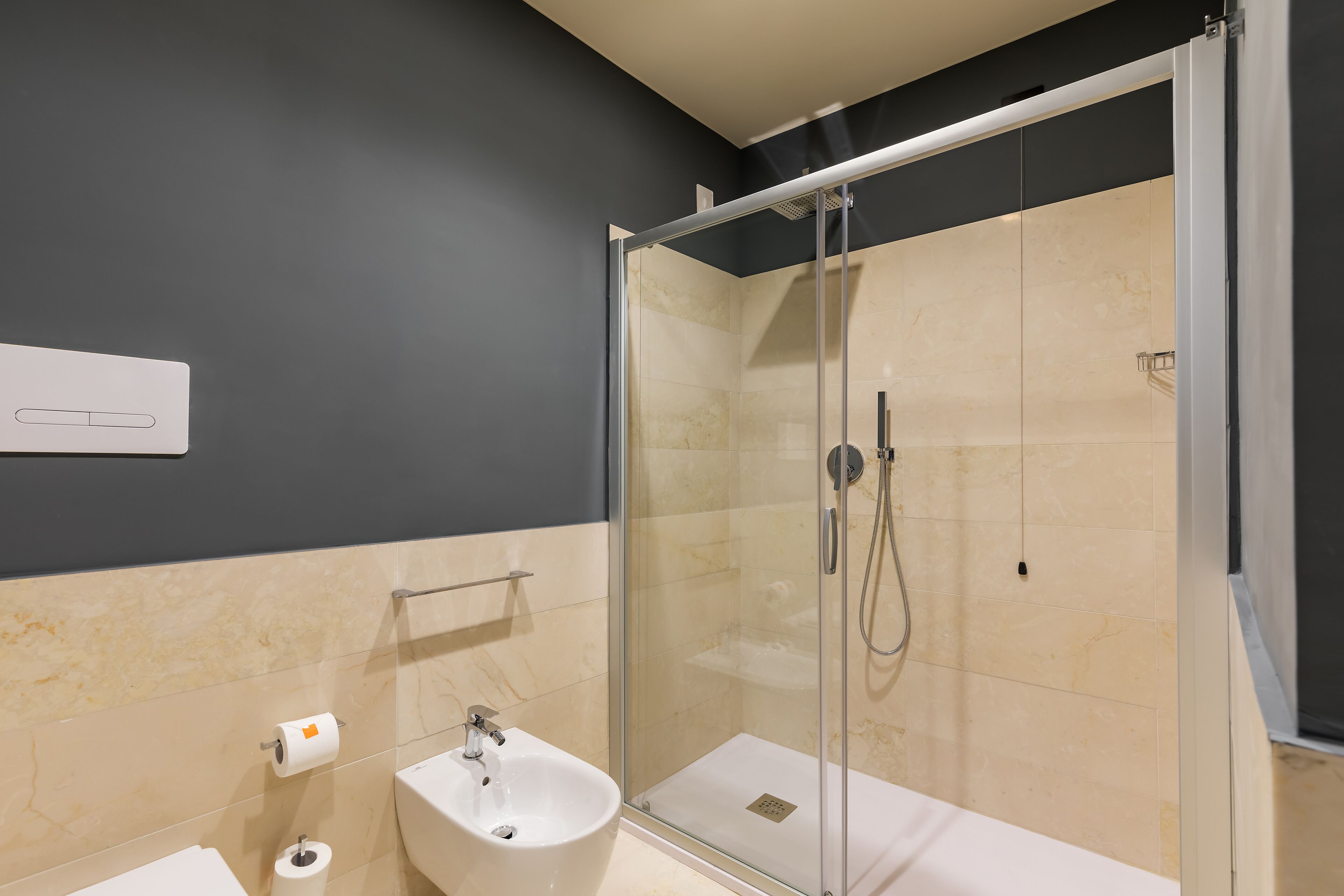 Een moderne badkamer met een douche met glazen wand, een wastafel en een toilet.