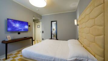 A hotel room with a large bed, a flat-screen TV mounted on the wall, a bedside table, and a check-in sign.
