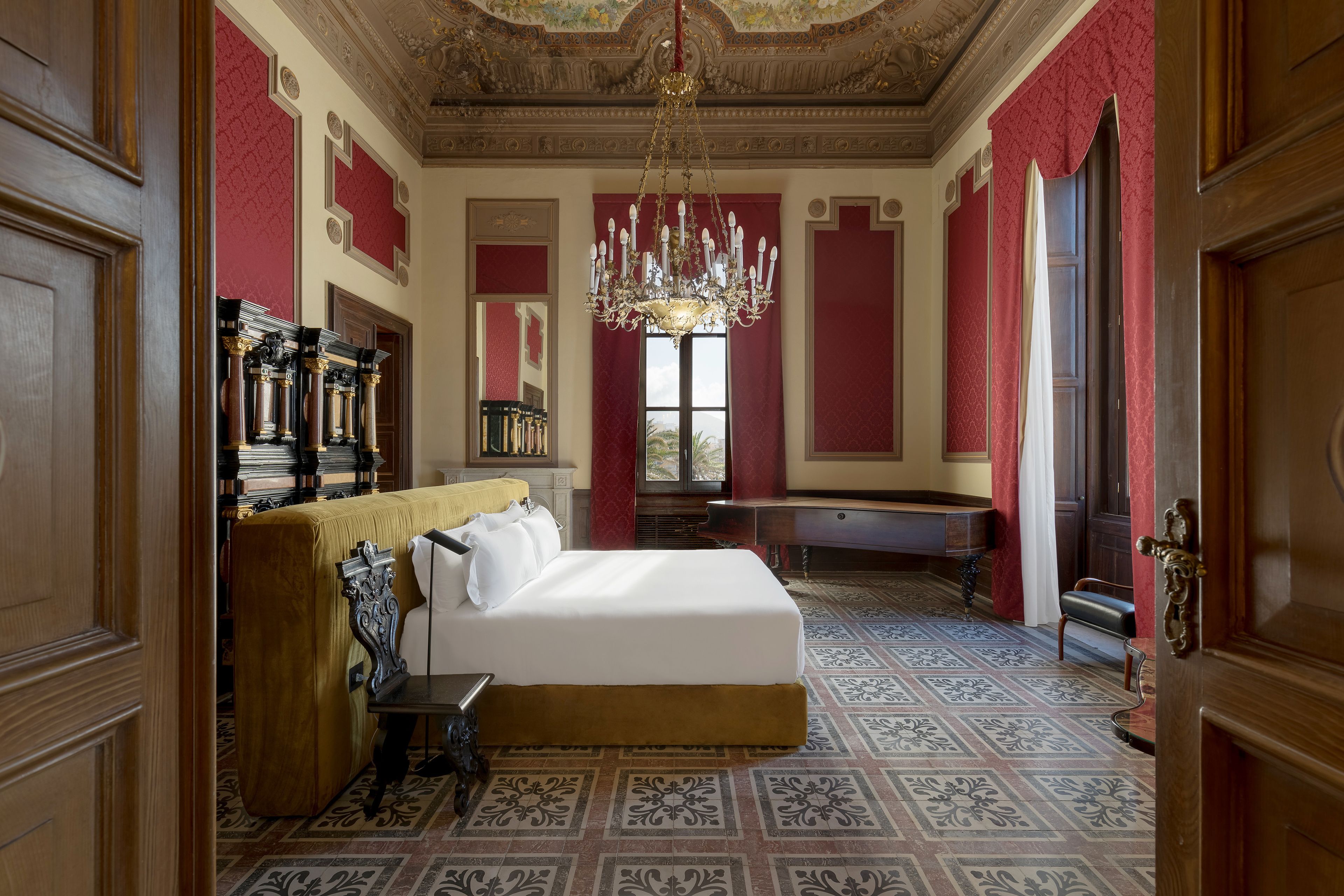 A luxurious bedroom with a large bed, ornate chandelier, and classic decor.