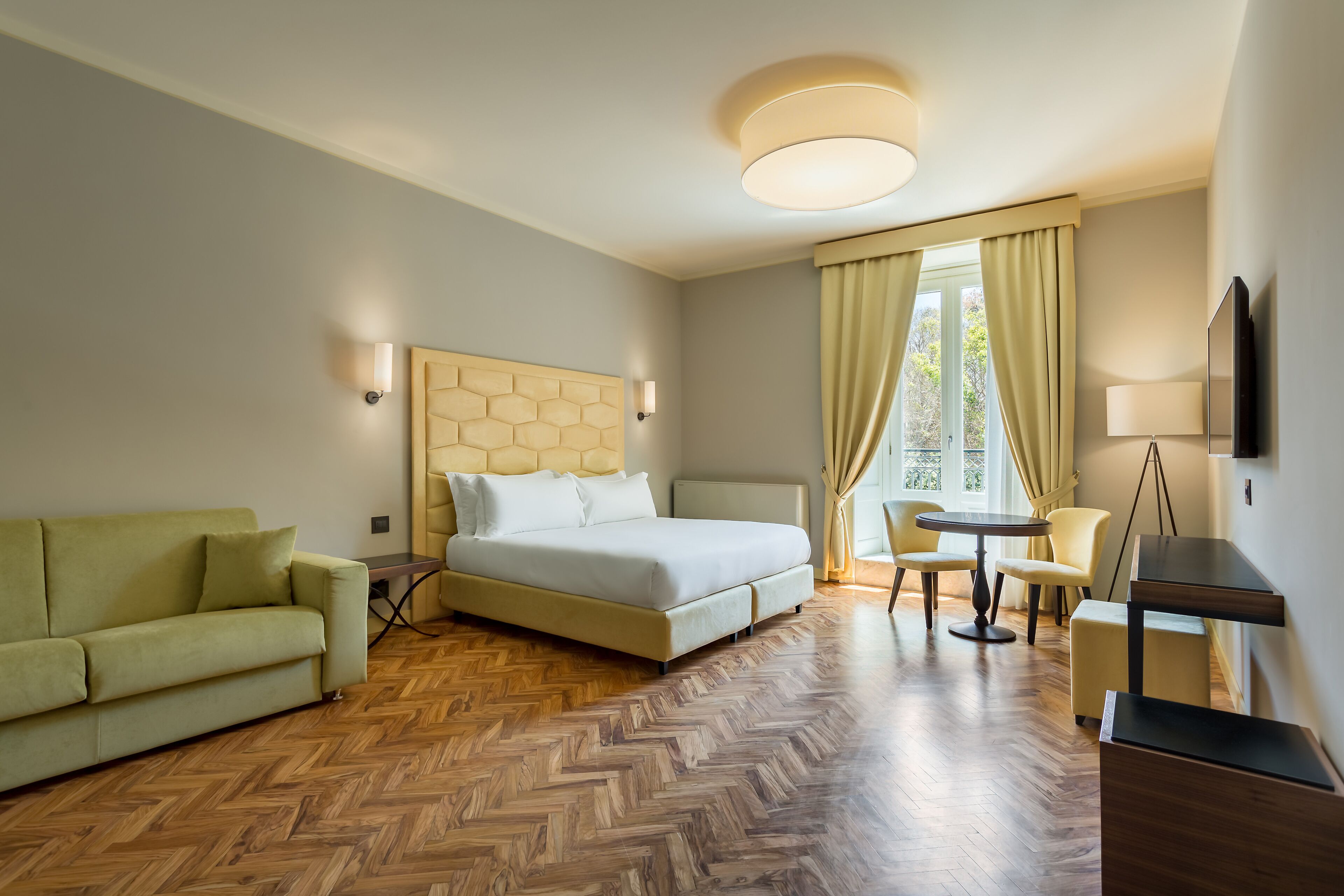 Una camera d'albergo con un letto, un divano, un tavolo da pranzo e una televisione.