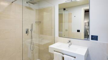 A modern bathroom with a glass-enclosed shower, a white sink, and a large mirror.