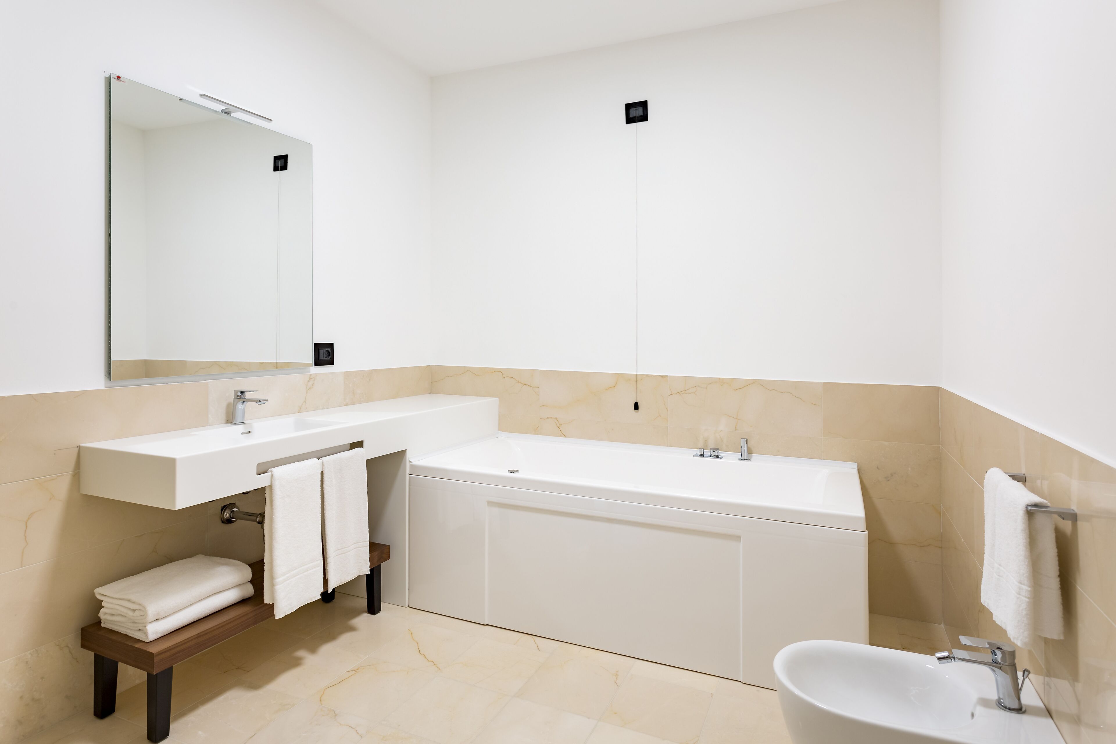 Ein modernes Badezimmer mit einem großen Spiegel, einer Badewanne, einem Waschbecken und einer Toilette.