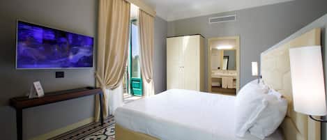 Een hotelkamer met een bed, een televisie, een bureau, een kledingkast en een badkamer die door een open deur zichtbaar is.