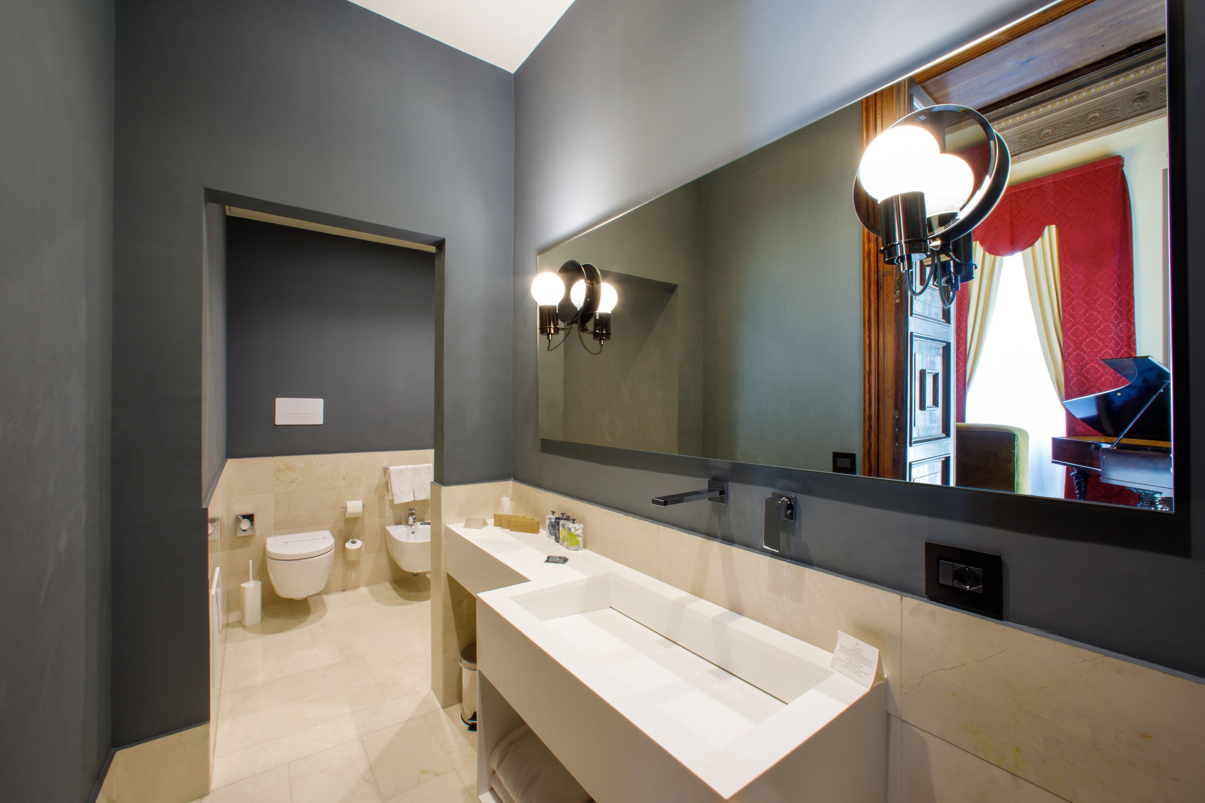 A modern bathroom with a large mirror, a white sink, and a toilet.