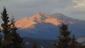 A mountain landscape with a prominent peak, surrounded by evergreen trees. -  Denali Wildlife Moose Cabin  Luxury with a touch of Rustic (Healy)