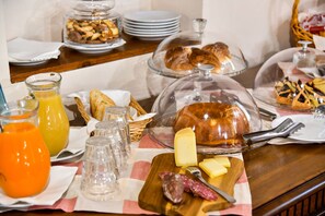 A breakfast buffet with various food items, including pastries, cheese, and meats, on a wooden table. - Agriturismo La Valle Dei Bronzetti (Cascia)