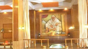 A room with a wooden floor, a large painting of a seated figure, and a small altar with candles. - Hotel Sharan (Rahata)
