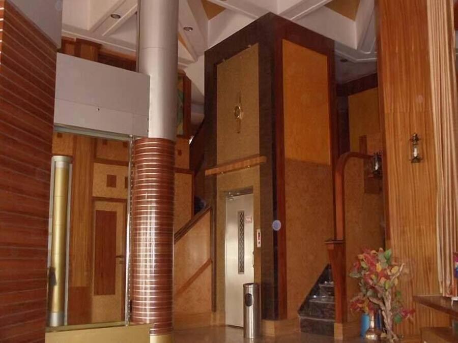 A lobby with a staircase, a reception desk, and a decorative plant.