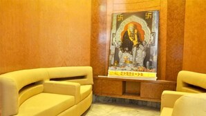 A lobby with a yellow sofa, a poster on the wall, and a marble floor. - Hotel Sharan (Rahata)
