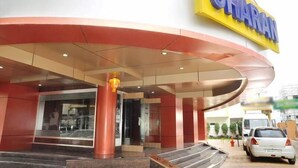 A hotel entrance with a curved roof, a prominent yellow sign, and a staircase leading to the entrance. - Hotel Sharan (Rahata)