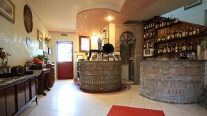 Zona de bar con mostrador de ladrillo, estanterías con botellas y una alfombra roja.